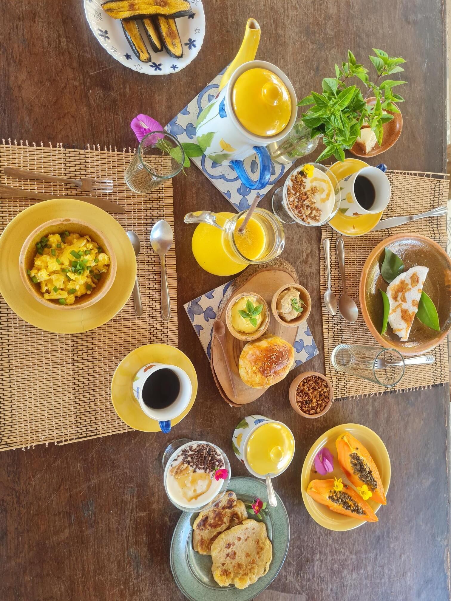 Une table de petit-déjeuner avec divers plats, notamment des œufs brouillés, des toasts et des fruits.