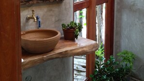 Un baño rústico con un lavabo de madera, un espejo y plantas en macetas.