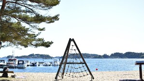A beach with a wooden swing set, boats, and a clear view of the water. - Awesome apartment in Søgne with sauna (Søgne)