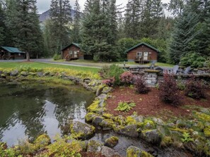 Una cabaña tipo lodge con un estanque y un camino de piedra.