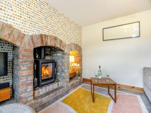 A cozy living room with a brick fireplace, a table with glasses, and a framed picture on the wall. - 1 bedroom accommodation in Stickford, near Spilsby (Stickford, near Spilsby)