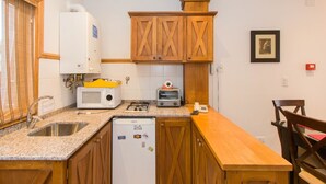 Una cocina compacta con armarios de madera, microondas, tostadora y refrigerador.