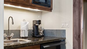 Una cocina con armarios de madera, microondas integrado, cafetera y lavavajillas.