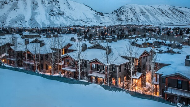 Un pueblo cubierto de nieve con casas de madera y una montaña al fondo.