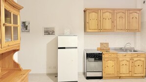 A kitchen with wooden cabinets, a white refrigerator, a stove, and a dishwasher. - M333 - Marcelli, cozy two-room apartment 200 meters from the beach (Marcelli)