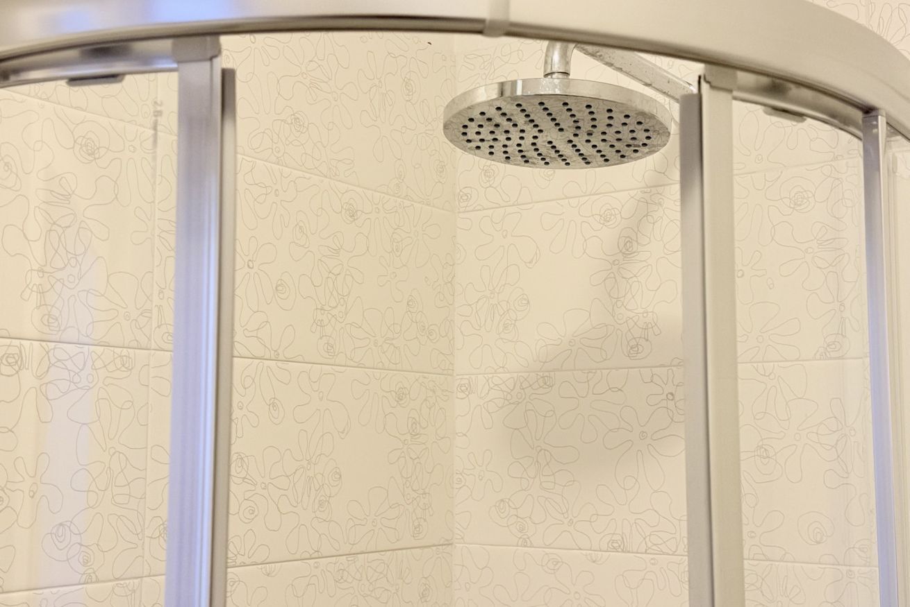 Una ducha con un estampado floral en las paredes y un cabezal de ducha circular.
