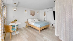 Un dormitorio moderno con una cama de madera, una mesa redonda blanca y una silla.