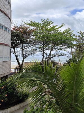 Un edificio con fachada de tejas, una palmera y vista al océano.