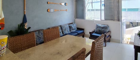 A dining area with a table and chairs, a sofa, and a window with blinds.