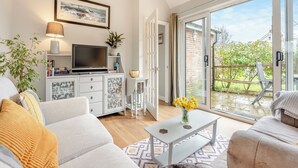Una sala moderna con un sofá, una mesa de centro y un televisor sobre un mueble.