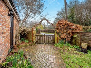 A brick building with a wooden gate and a paved pathway leading to a gated entrance. - 1 bedroom accommodation in Heathfield (Heathfield)