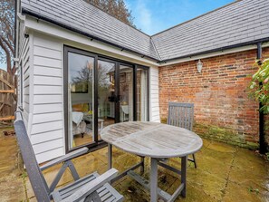 Une maison avec un patio, une table et une chaise.