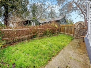A residential backyard with a wooden fence, a grassy lawn, and a wooden gate. - 1 bedroom accommodation in Heathfield (Heathfield)