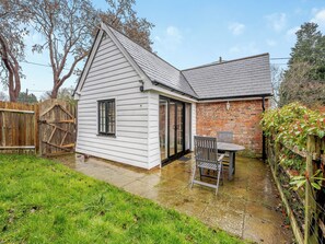 A house with a covered patio, a brick wall, and a wooden fence. - 1 bedroom accommodation in Heathfield (Heathfield)