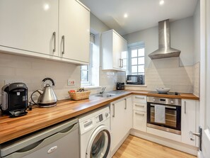 A modern kitchen with white cabinets, a Bosch washing machine, a microwave, and a stainless steel range hood. - 1 bedroom accommodation in Heathfield (Heathfield)