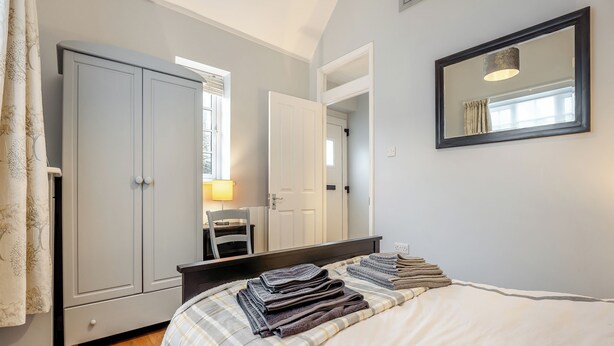 Un dormitorio con cama, silla, escritorio, armario y espejo.