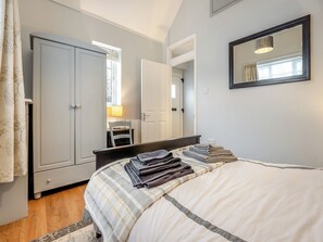 A bedroom with a bed, a chair, a desk, a wardrobe, and a mirror. - 1 bedroom accommodation in Heathfield (Heathfield)