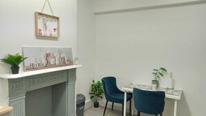 Un'area pranzo con camino, due sedie, un tavolino e una pianta in vaso.