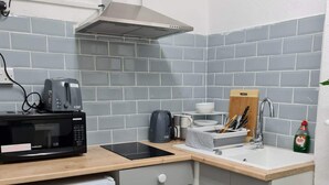Una cucina compatta con forno a microonde, tostapane e lavello.