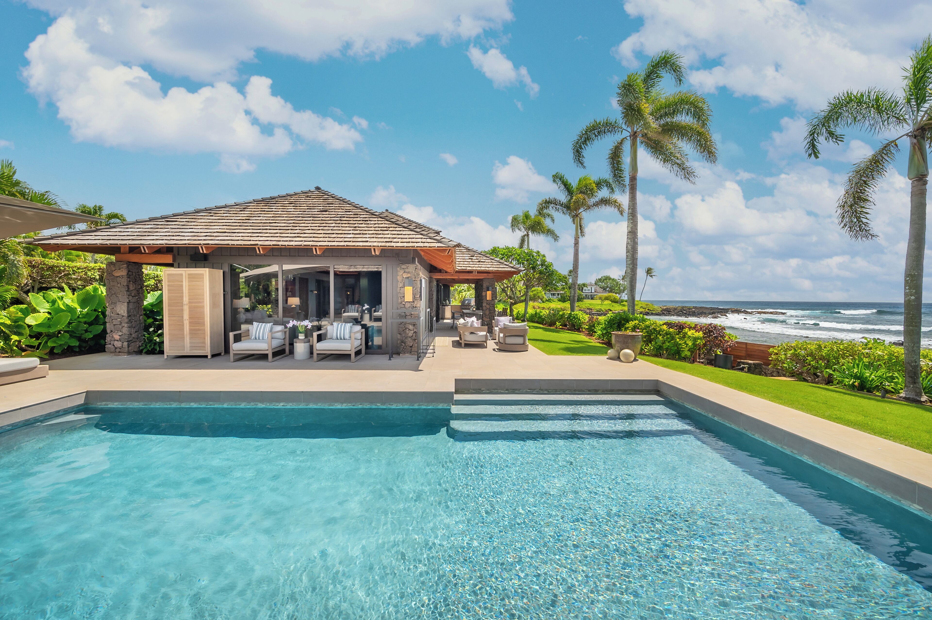 A swimming pool with a covered seating area and a view of the ocean.