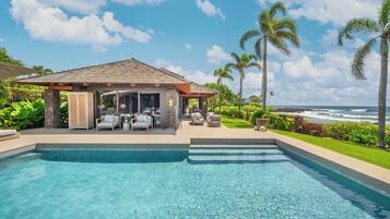 A swimming pool with a covered seating area and a view of the ocean.