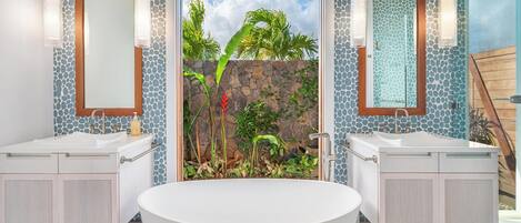 Ein modernes Badezimmer mit einer freistehenden Badewanne, zwei Waschbecken und einem großen Spiegel.