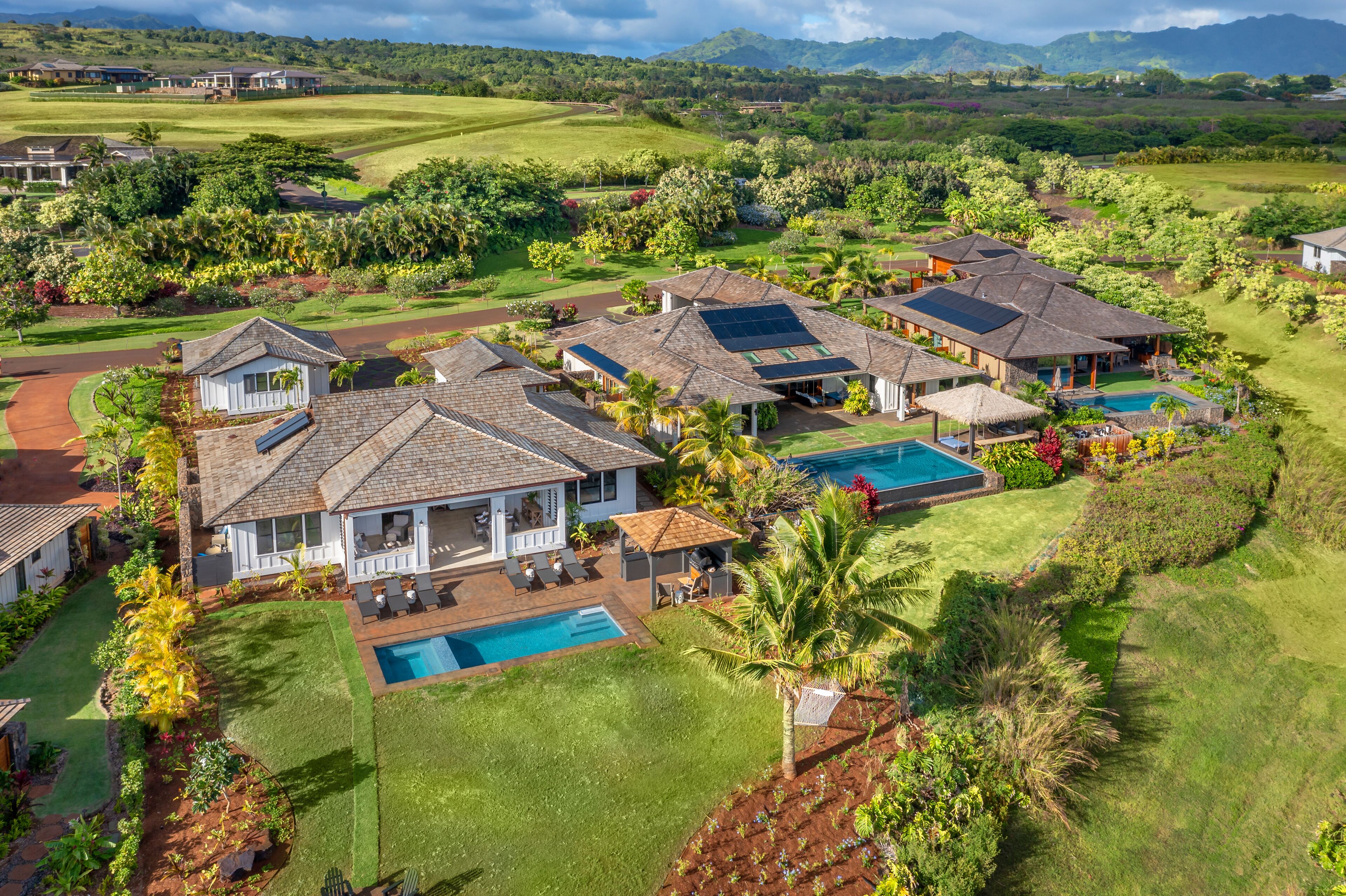 Zona residencial com casas, piscina e vegetação exuberante.