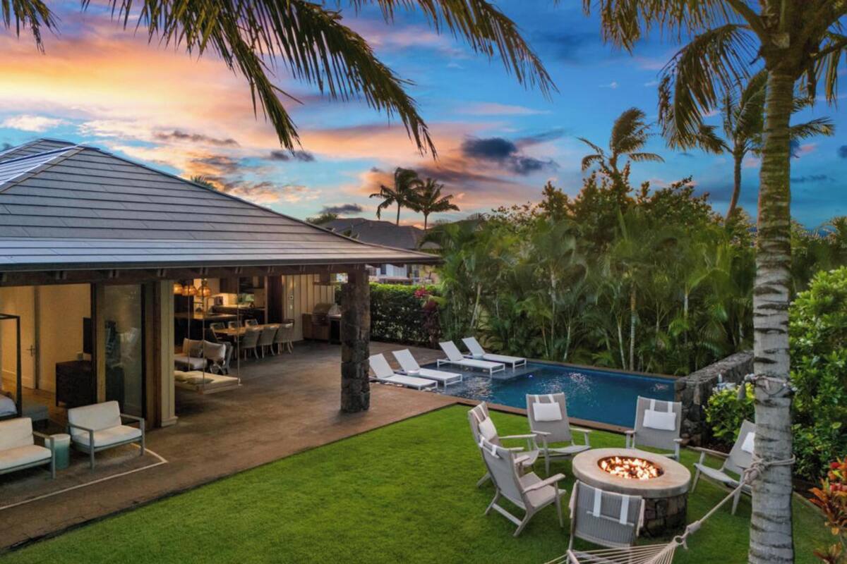 A modern house with a covered patio, a swimming pool, and a fire pit area.