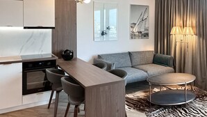 A modern kitchen with a central island, grey sofa, and a round table with a lamp. - 1 bedroom awesome apartment in Gdynia (Gdynia)