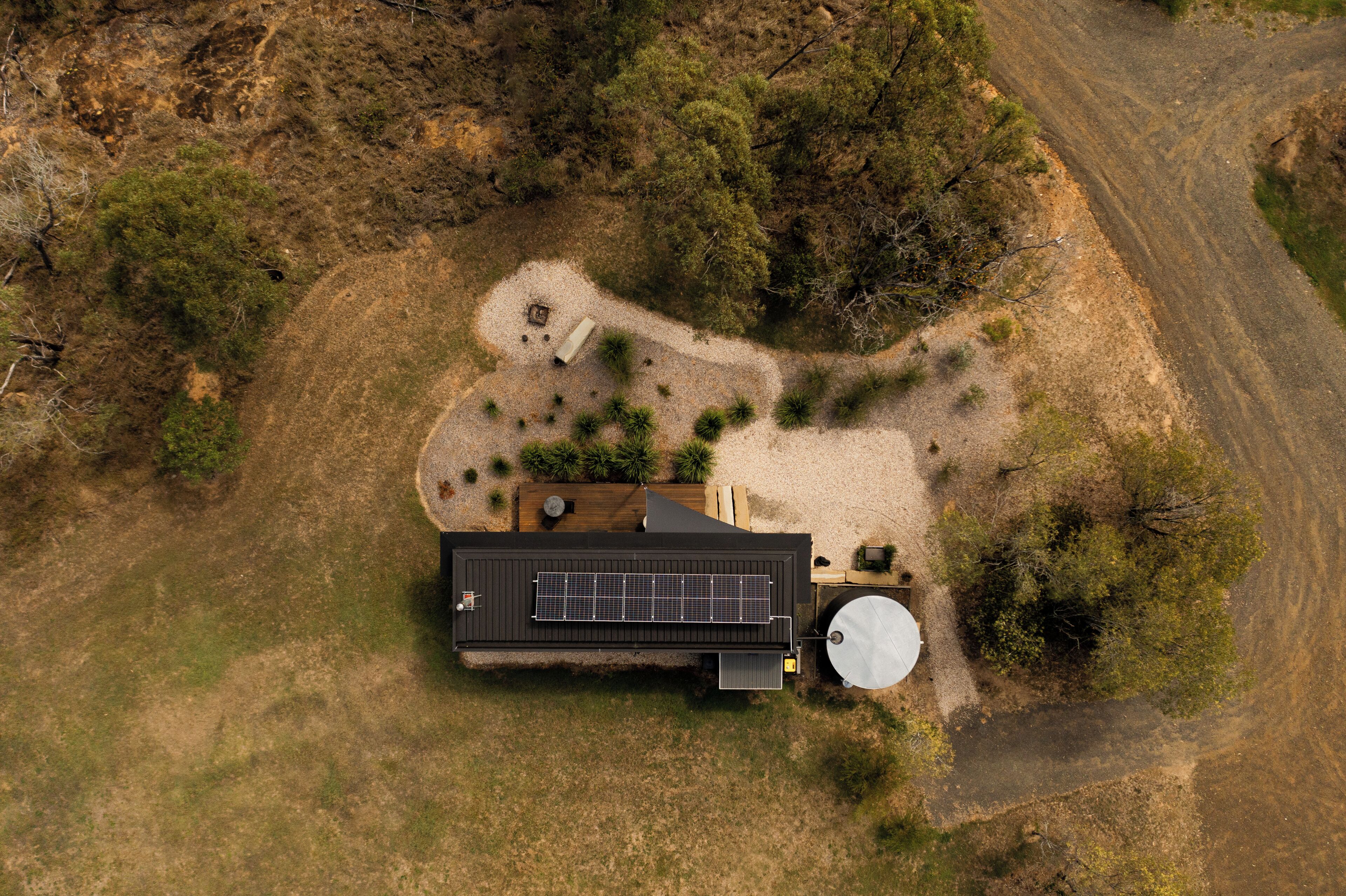 An aerial view of a modern house with a solar panel, a water tank, and a well-maintained garden.