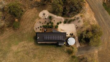 An aerial view of a modern house with a solar panel, a water tank, and a well-maintained garden.