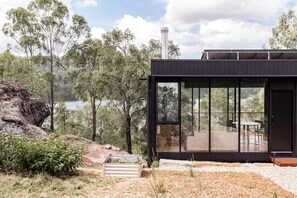 A modern building with large windows, a chimney, and a view of a lake and trees.