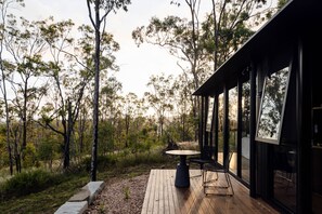 A wooden deck with a table and chairs, surrounded by trees.