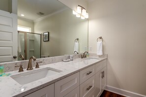 Un baño con lavamanos doble, encimera de mármol y un espejo grande.