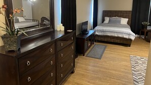Een hotelkamer met een bed, een bureau met computer, een dressoir en een grote spiegel.