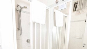 Une salle de bain avec une douche à parois de verre, un lavabo avec un miroir et des toilettes.
