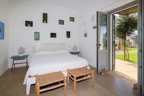 A bedroom with a bed, two nightstands, a door to a balcony, and several wall-mounted decorations. - 3194 Masseria Il Carrubo by Perle di Puglia (Salve)
