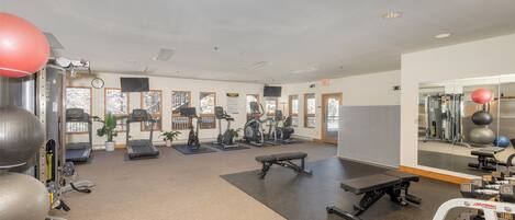 A gym with treadmills, elliptical machines, and free weights.