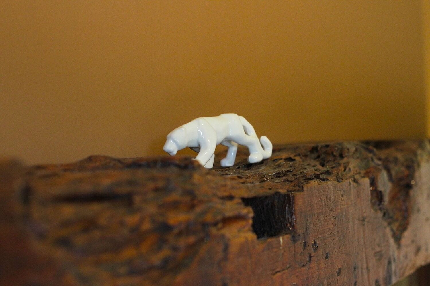 A small white figurine of a polar bear on a wooden surface.