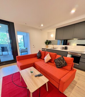 Uma sala de estar moderna com um sofá seccional vermelho, uma mesa de centro de madeira e um tapete vermelho.