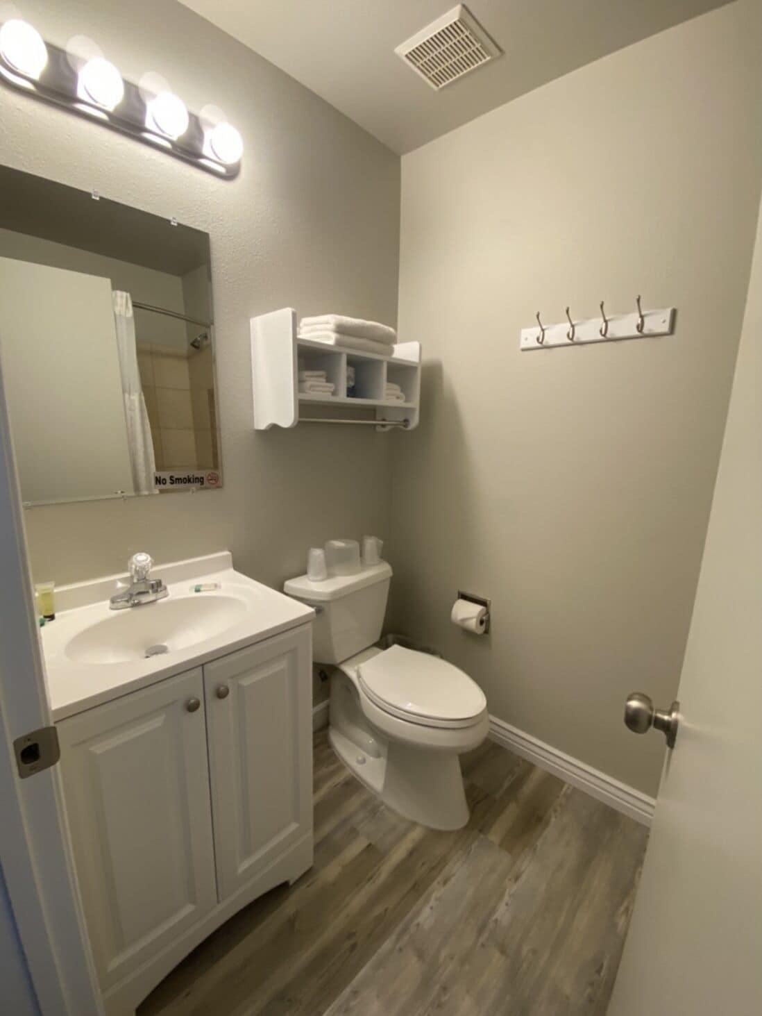 A bathroom with a vanity, sink, mirror, and a towel rack.