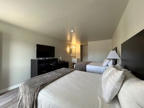 A hotel room with two beds, a TV, a desk with a computer, and a bathroom. - HWY 50 Inn (Ely)