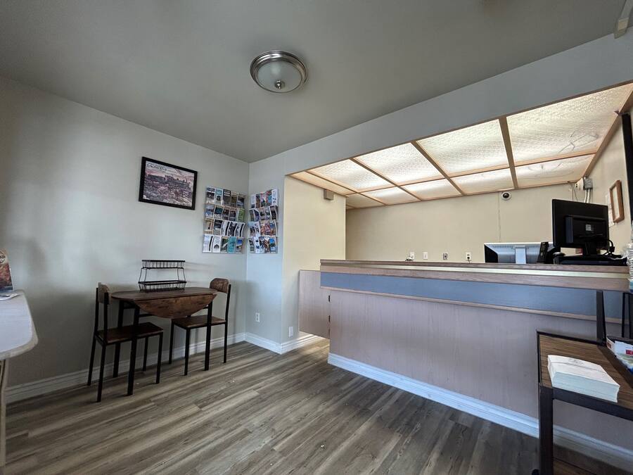 Eine kleine, moderne Küche mit Esstisch und Stühlen aus Holz, einer integrierten Arbeitsplatte und einer Deckenleuchte.