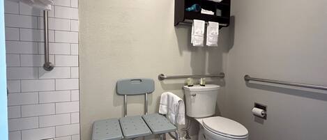A bathroom with a toilet, a sink, a shower, and a grab bar.