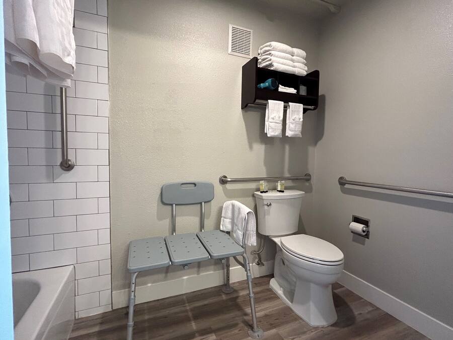 A bathroom with a toilet, a sink, a shower, and a grab bar.