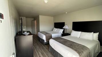 Une chambre d’hôtel avec deux lits, un bureau avec un ordinateur, une lampe et une armoire.