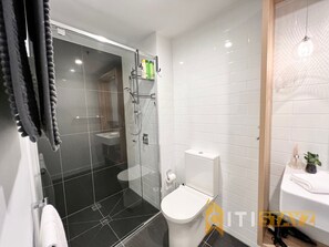 Un bagno moderno con cabina doccia in vetro, un water bianco e un lavabo.