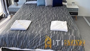 A modern bedroom with a large bed, a nightstand, a lamp, and an air conditioning unit. - Splendid 2bd 1bth 1csp Apt - Superb CBD Location (Reid)