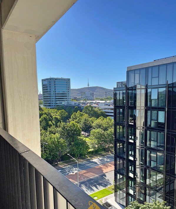 Un balcon offrant une vue sur des immeubles modernes, une tour et un espace vert aménagé en parc.