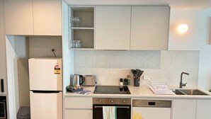 Cozinha compacta com geladeira, torradeira, forno e pia.